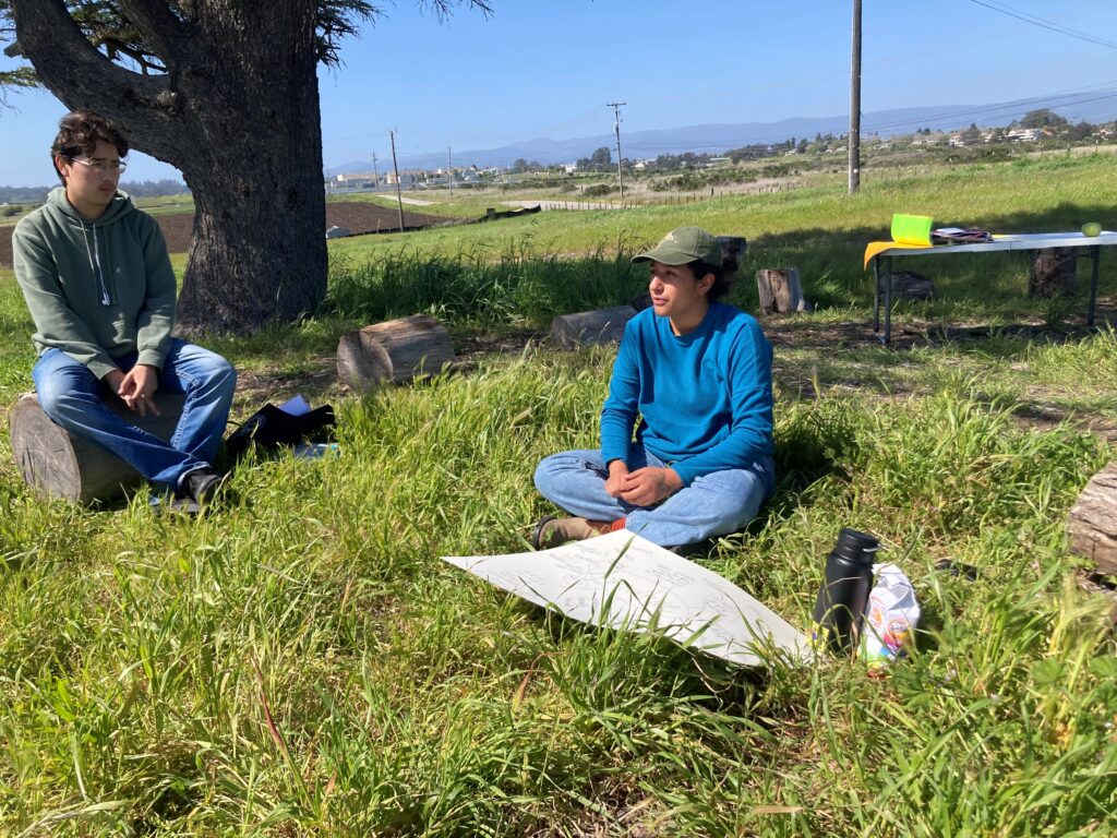 Alma Leonor Sánchez teaching students about organic farming in a circle outdoors as part of CCOF’s education programs.